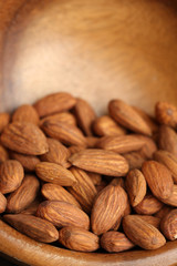 Almonds in bowl on color wooden background