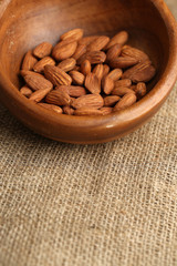 Almonds in bowl on sackcloth background