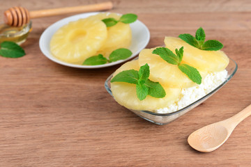 Bowl of tasty cottage cheese with pineapple on wooden table