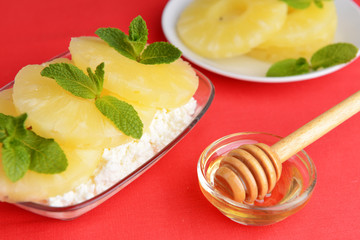 Bowl of tasty cottage cheese with pineapple, on red background