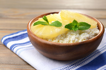 Bowl of tasty cottage cheese with pineapple on wooden table