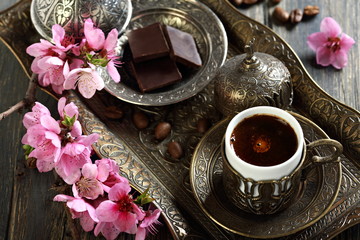 Turkish coffee, chocolate and branch with pink flowers.