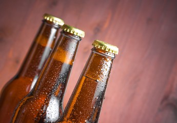 three tilted bottles of fresh beer with drops and space for text