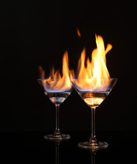 Glasses with burning alcohol on black background