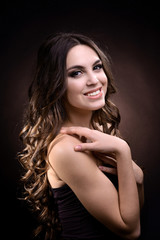 Naklejka premium Beautiful young woman with long hair on dark brown background