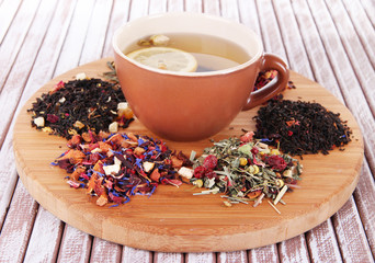 Cup of tea with aromatic dry tea on stand on wooden background