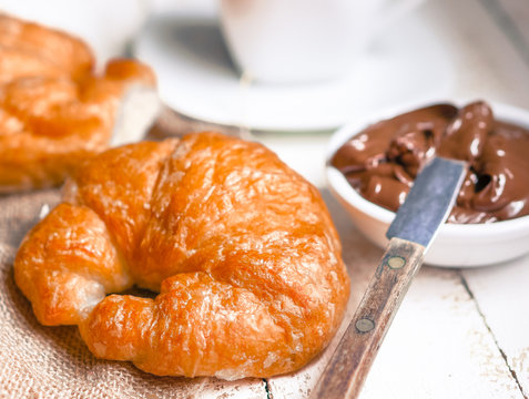 Fresh baked croissants with chocolate cream and hot cocoa on woo