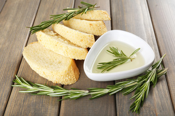 Fresh bread with olive oil and rosemary on wooden table