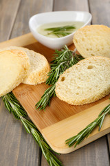 Fresh bread with olive oil and rosemary on wooden table