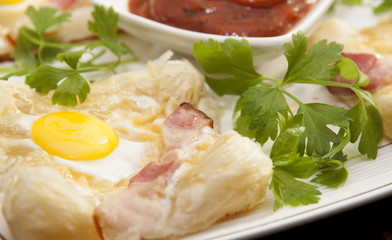   Sandwich with quail egg and ham on the puff pastry.