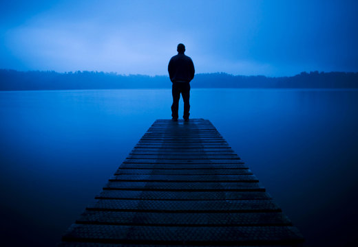 Man Standing on a Jetty by Tranquil Lake