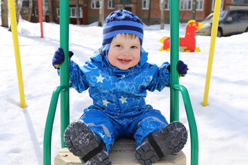 happy baby age of 18 months on seesaw in winter