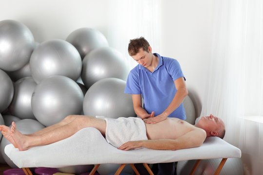 therapist massaging middle age  man' s abdomen