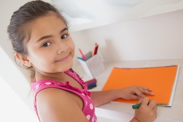 Young girl drawing on orange paper