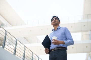 indian male business man holding a coffe with office background