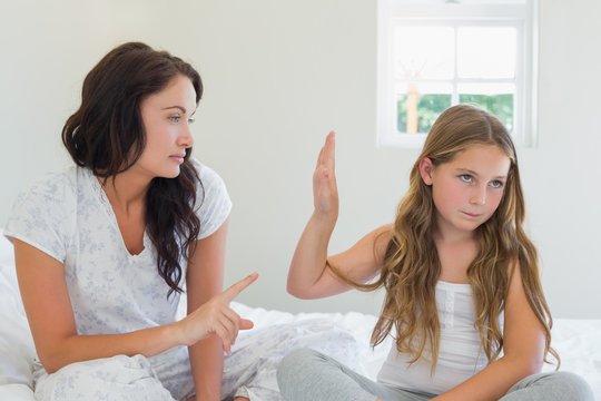 Girl Showing Stop Gesture To Angry Mother In Bed