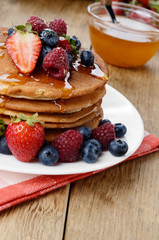 Pancakes with berries and honey closeup