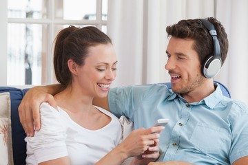 Couple listening music with mobile phone on couch