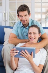 Fototapeta premium Happy couple using digital tablet on couch