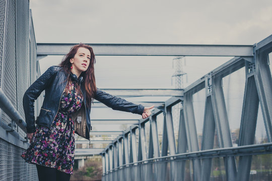 Pretty girl with long hair hitchhiking on a bridge