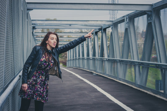 Pretty girl with long hair hitchhiking on a bridge