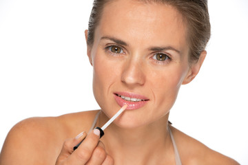 Young woman applying lip gloss