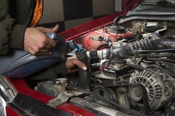 Car repairman pouring antifreeze into old engine