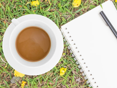 cream notebook with pen and cup of coffee