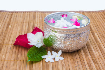 Water with jusmine and roses corolla in bowl on bamboo mat