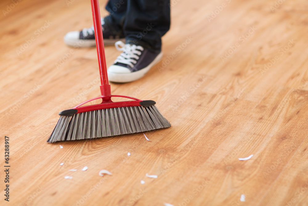 Wall mural close up of male brooming wooden floor