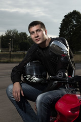 Fototapeta na wymiar Closeup portrait of young biker sitting on sportmotorcycle