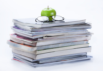green apple and glasses on magazine and book stack