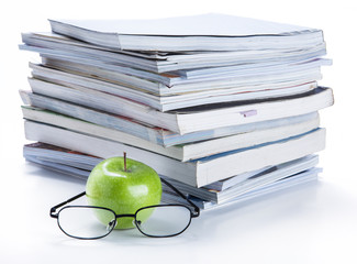 green apple and glasses with magazine and book stack