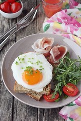 Fried egg with fresh bread,prosciutto,arugula and tomatoes