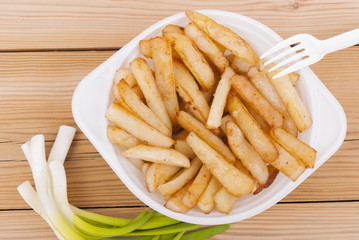Fried potatoes with onions on a wooden table.