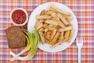 Fried potatoes in a plate on a tablecloth.