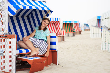 Young happy woman sitting and relaxing on beach chair on the bea