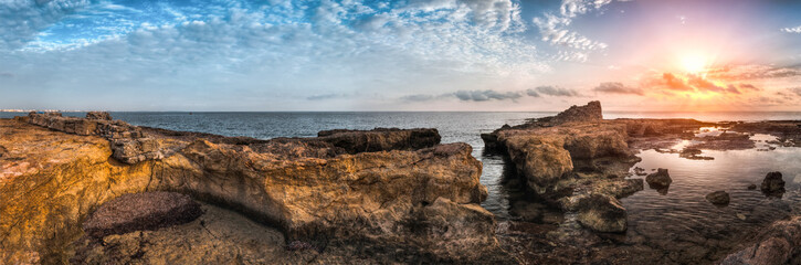 Sunset over the Sea and Rocky Coast with Ancient Ruins