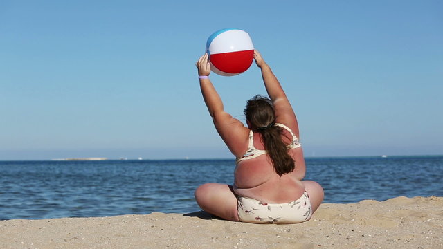 overweight woman doing gymnastics on beach
