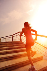 fitness young asian woman running sunrise seaside stairs