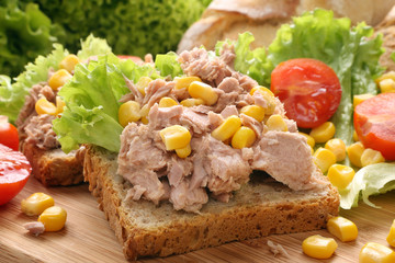 Sandwich with tuna, corn and tomato on wood