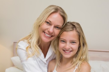 Mother and girl smiling in bedroom