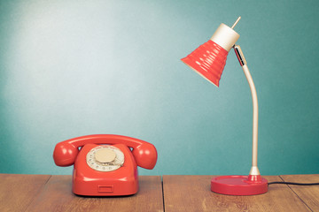 Retro red telephone and desk lamp on wood table