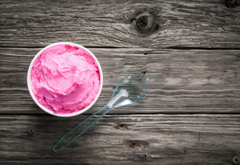 Tub of berry ice cream on a rustic wood table