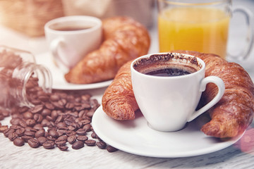 Two cups of coffee with croissants and a cup of orange juice