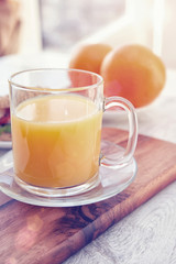 Cutting board with oranges and a cup of juice