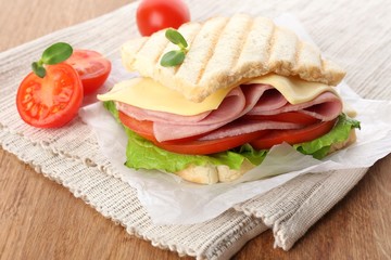 Tasty sandwich with ham on wooden table
