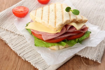 Tasty sandwich with ham on wooden table