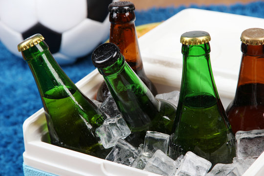 Ice chest full of drinks in bottles on color carpet background