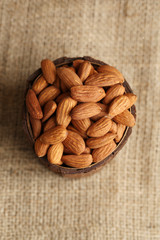 Almonds in bowl on sackcloth background
